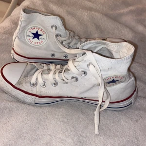 Converse All Star vita high tops - Säljer ett par klassiska vita Converse All Star high tops i storlek 38. Skorna har snörning, rund tå och platt sula. De är tillverkade i textil med gummisula. Ikoniska skor. 