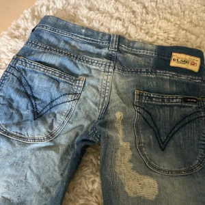 unika lågmidjade bootcut jeans - Säljer ett par blå bootcut jeans från G - lago med låg midja och snygga detaljer. Jeansen har markerade bakfickor med mörkblå sömmar och patchade partier framtill. Klassisk denim modell med cool tvättad look. Skriv för mått