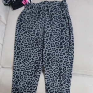 Leopardmönstrade mjukisbyxor - Superbekväma mjukisbyxor med grått och svart leopardmönster. Byxorna har resår i midjan och är gjorda i ett mjukt material som känns skönt mot huden. Perfekta för chill dagar hemma eller när du vill sticka ut lite extra.