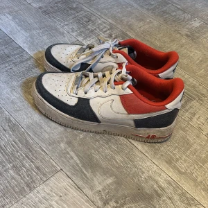 Nike Air Force 1 sneakers i vitt och rött - Snygga air forces i vit blå och röd, kommer tvätta dom så gott de går innan leveransen och pris går att få ner vid snabb affär 