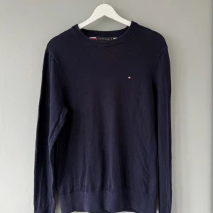 Mörkblå tröja Tommy Hilfiger XS - Mörkblå långärmad tröja från Tommy Hilfiger i en mjuk bomulls- och kashmirblandning. Klassisk rund halsringning och diskret logga broderad på bröstet. Perfekt för dig som gillar stilrena och bekväma plagg.