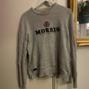 Grå stickad tröja från Morris! - Säljer en grå stickad tröja från Morris med rund hals och broderad logga framtill. Tröjan har ribbade muddar vid ärmslut och nederkant, samt lång ärm. Perfekt för dig som gillar klassisk och stilren design! Vid frågor är det bara att skriva!