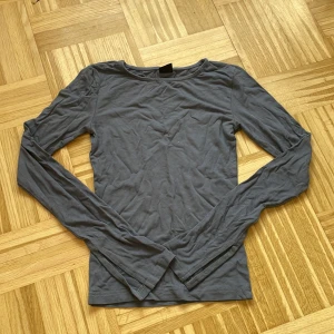 Blå långärmad topp från Gina Tricot - En basic blå långärmad topp från Gina Tricot i mjuk bomull. Enkel och stilren design med rund halsringning och smal passform. Perfekt att styla med jeans eller kjol för en clean look.