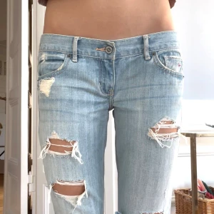 Lågmidjade bootcut jeans - Säljer mina absoluta favorit jeans, de sitter helt perfekt och har jätte snygga slitningar. De är ifrån Hollister! Midjemåttet är 39 cm, Innerbenslängden är 79 cm. De har inga defekter! Jag köpte jeansen för 1500 kr och de är väldigt eftertraktade! Kom privat vid fler funderingar 💕💕