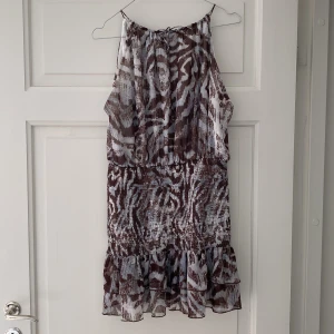  Zebraklänning från Zara - Fin kort klänning från Zara med brunt och ljusblått zebramönster. Klänningen är ärmlös med volangkant nertill och har en luftig, lätt känsla.             Modellbilden är en lånad bild.