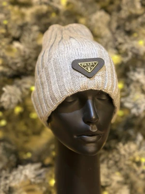 Beige ribbstickad mössa - Snygg beige ribbstickad mössa med uppvikt kant. Perfekt för kalla dagar och enkel att matcha med olika outfits. Klassisk modell som sitter skönt på huvudet och ger en avslappnad stil.