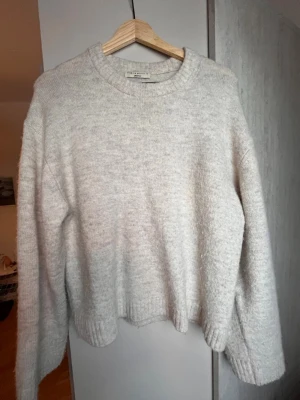 Beige stickad tröja Gina Tricot - Mysig beige stickad tröja från Gina Tricot i premiumkvalitet. Tröjan har rund halsringning, långa ärmar och ribbstickade muddar vid ärmslut och nederkant. Perfekt för lager-på-lager och chill dagar.