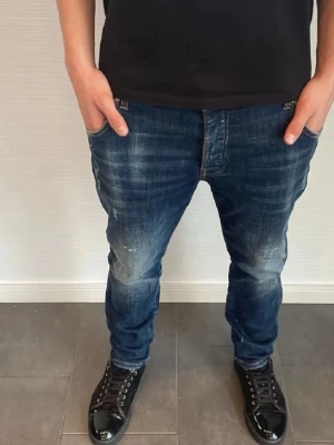 Mörkblå jeans med slitningar - Snygga mörkblå jeans med slitna detaljer och tvättade partier för en cool look. Jeansen har klassisk femficksmodell och rak passform. Perfekta för dig som gillar en avslappnad men trendig stil.