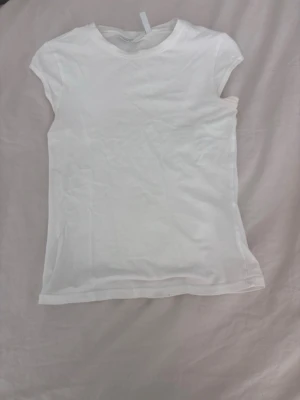 Vit basic t-shirt - En enkel vit t-shirt med rund hals och korta ärmar. Perfekt att matcha med jeans eller shorts för en clean och stilren look. T-shirten har en klassisk passform och är ett måste i garderoben.