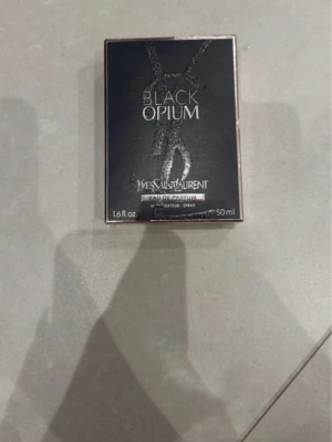 Yves Saint Laurent Black Opium 50ml - Black Opium Eau de Parfum från Yves Saint Laurent i en snygg svart och glittrig flaska med rund orange detalj. Flaskan rymmer 50 ml och har en modern, lyxig design som sticker ut på parfymhyllan.