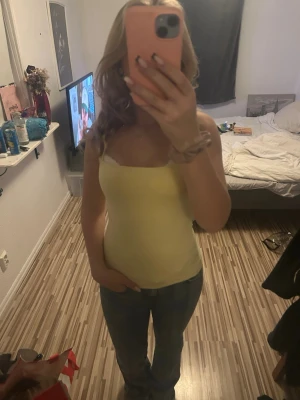 Ljusgul ärmlös linnetopp - Snygg ljusgul linnetopp med smala axelband och figurnära passform. Perfekt till jeans eller kjol för en fräsch och enkel look. Mjuk och stretchig känsla, passar dig som gillar minimalistisk stil. Perfekt till våren/sommaren!! Ifrån New Yorker. Nypris-vet ej Säljer för-20. Säljs billig då ja vill bli av med den❣️ Storlek M men passar mig som är S🥰🥰