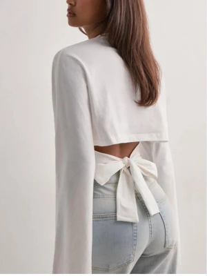 Vit omlottopp med knytband - Populär topp från Nelly med öppen rygg och ett knytband. Knappt använt den, som ny! Slutsåld överallt.  Nypris: 299 kr