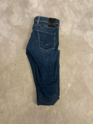 Blå anbass replay jeans - Snygga blå jeans från Replay i modellen slim fit. Fint skick bara att lappen där de står modellen”Anbass” har trillat bort. Som man ser på bild 5 har sömmen gått upp lite på fickan, samma på andra fickan också men de är inget man märker av. Hör av er vid frågor! 