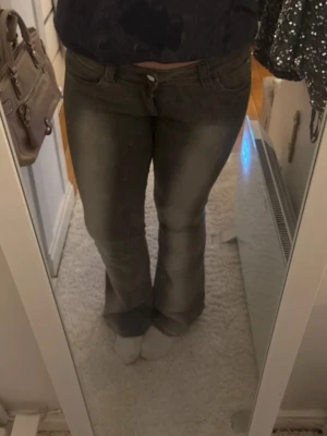 Grå bootcut jeans med slitningar - även så kallade kvargbyxorna! - Säljer ett par gråa bootcut jeans med snygga slitningar och tvättade detaljer. Jeansen har klassisk femficksmodell och normal passform i midjan. Perfekta för dig som gillar en avslappnad men ändå trendig look.