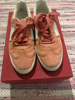 Valentino sneakers i rosa mocka - Snygga sneakers från Valentino i modellen Flycrew i rosa mocka med vita detaljer och matchande rosa snörning. Skorna har en klassisk låg profil och rund tå, samt en vit sula som ger en fräsch kontrast. Perfekta för dig som vill ha en stilren och trendig look.äkthetsbevis från vestiaire medföljer