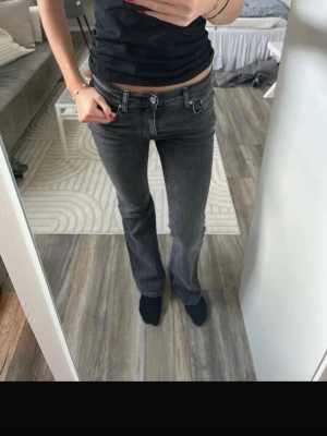 Grå bootcut jeans från Gina tricot  - Snygga grå jeans från Gina tricot i bootcut-modell. Jeansen har låg midja och klassisk femficksdesign. Perfekta till vardagslooken och passar till det mesta. Materialet är mjukt och stretchigt jeans-tyg för skön passform.