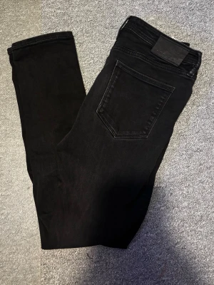 Svarta skinny jeans 28/30 - Säljer ett par svarta skinny jeans i storlek 28/30. Jeansen har klassisk femficksdesign och är tillverkade i stretchigt denimtyg för en tight och bekväm passform. Perfekta till alla typer av outfits.