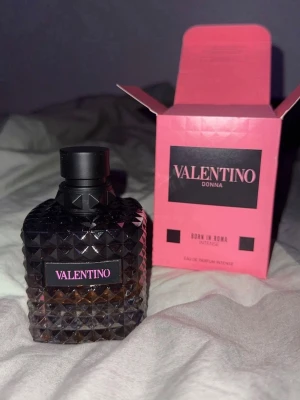 Valentino Donna Born In Roma Intense - Valentino Donna Born In Roma Intense är en lyxig parfym i en mörk, diamantmönstrad glasflaska med svart kork och rosa etikett. Förpackningen är rosa med svarta detaljer och logotyp. Doften är elegant och modern, perfekt för dig som vill sticka ut.
