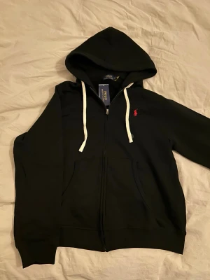 Svart hoodie från Polo Ralph Lauren - Säljer pga att den är för stor. Helt ny och aldrig använd innan. Tillkommer i original förpackning samt lappar sitter kvar. Priset kan diskuteras