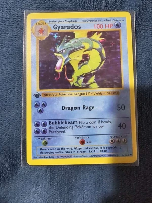 Gyarados #6 1st Edition  - Säljer ett Gyarados Pokémonkort från Base Set, original från 1999. Kortet har en gul ram, holografisk bild och blå bakgrund. Engelskt språk och klassisk design med 100 HP. Perfekt för samlare eller Pokémonfans.