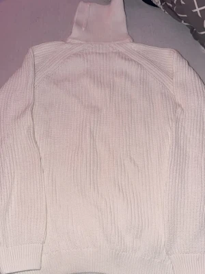 Vit oversize polotröja från Zara - Säljer en krämvit stickad polotröja från Zara. Tröjan har ribbstickad struktur, hög polokrage och långa ärmar. Perfekt för kalla dagar och enkel att styla till olika outfits.