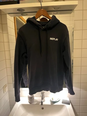 Mörkblå hoodie från Replay - Snygg mörkblå hoodie från Replay med vit logga på bröstet. Klassisk modell med huva och dragsnören, samt ribbade muddar vid ärmslut och nederkant. Perfekt för en avslappnad och trendig stil. Bvsa!