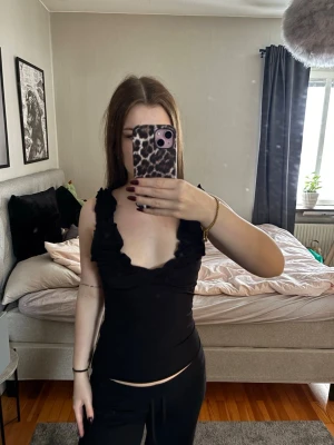 Svart volanglinne med breda axelband - Supersnygg svart linnetopp med breda axelband och volangdetaljer. Toppen är figurnära och har en djup v-ringning framtill❤️