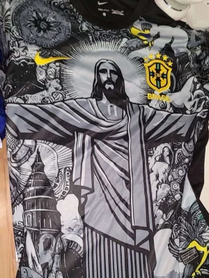 Nike Brasil grafisk fotbollströja - Unik fotbollströja från Nike med Brasil-logga och grafiskt tryck av Kristusstatyn i Rio de Janeiro. Tröjan har svart, grå och gul färgskala med detaljerade illustrationer och Nike Swoosh på bröstet. Perfekt för dig som vill sticka ut på planen.