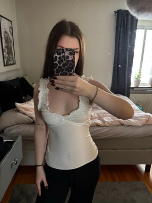 Vit volanglinne med djup rygg - Supersött vitt linne med volangdetaljer längs axelbanden och djup urringning både fram och bak. Figurnära passform och stretchigt material. Aldrig använd❤️