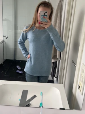 Ljusblå stickad tröja - Mysig ljusblå stickad tröja med rund halsringning och långa ärmar. Tröjan har en rak passform och ribbstickade muddar vid ärmslut och nederkant. Perfekt för lager-på-lager och enkel att matcha med jeans.