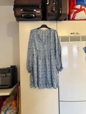 Blommig blå kortklänning Odd Molly - Supersöt blå kortklänning från Odd Molly med blommigt mönster, v-ringning och långa ärmar. Klänningen har en luftig passform och är gjord i mjuk bomull, perfekt för vår och sommar. Fina detaljer och avslappnad stil som känns både trendig och bekväm. Storlek 3 som enligt deras storleksguide motsvarar en L. Mycket fint skick, jag hittar inga synliga anmärkningar eller defekter. 