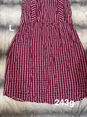 Rosa och röd mönstrad klänning - Klänning med rosa, röd och vit geometriska mönster. Klänningen har en lätt utställd kjol och är ärmlös, perfekt för varma dagar. Snygg och färgstark look som sticker ut.🌸 Fint använt skick. Storlek L