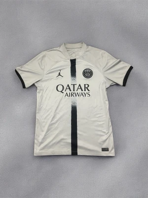PSG x Jordan tröja grå M - Jag har haft det lite det har lite fläckar på den men med en tvätt det kommer se helt ny. Snygg PSG x Jordan matchtröja i ljusgrått med svart vertikal rand och svarta detaljer. Tröjan har Paris Saint-Germain-logga, Jordan Jumpman-logga och Qatar Airways-tryck på bröstet. för maximal komfort vid fotboll.