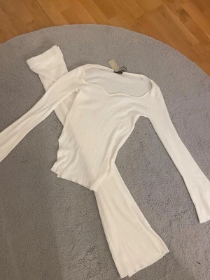 Vit ribbad långärmad topp från Boohoo - Säljer en vit ribbad långärmad topp från Boohoo i storlek S. Toppen har en snygg, något fyrkantig halsringning och är figurnära i modellen. Materialet är mjukt och stretchigt, perfekt för en clean och fräsch look. Passar dig som gillar minimalistisk stil. Aldrig använt 