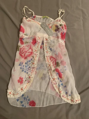Jättefin fairycore/coquette topp - Ny, oanvänd med etikett på! En jättevacker topp i tunt och skönt material, med fina blommor. Perfekt för coquette look fairycore, eller bara en liten cute och romantic look!   Det står att storleken är XL, men upplevs liten i storlek och motsvarar snarare en M!!!