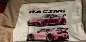 Berry Racing vit t-shirt med biltryck - Vit t-shirt från Berry Racing med stort tryck på ryggen av två rosa sportbilar och texten 'AUTO RACING'. Framsidan har Berry Racing-loggan i rosa och svart. Klassisk rund hals och korta ärmar. Perfekt för dig som gillar bilar och streetwear.