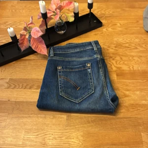 Dondup jeans - Snygga blå jeans från Dondup och slitna detaljer på framsidan. Klassisk femficksmodell med bruna sömmar och läderpatch med logga bak i midjan. Jeansen har låg midja och är tillverkade i stretchigt denim för en bekväm känsla.
