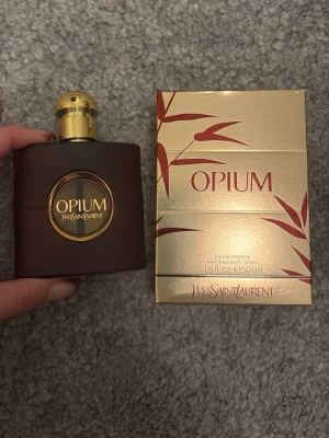 YSL Opium femme Eau de Parfum 50ml - YSL Opium Eau de Parfum, 50ml. NOTES TOP: Bergamot Accord Orange Accord Aldehydes HEART: Jasmin Accord Spicy Carnation Accord Rose Accord DRYDOWN: Orchid Vanilla Accord Amber Accord Patchouli Essence  This spicy and floral trail is a symbol of addiction since its creation. Never has a perfume provoked such emotion. Opium eau de parfum is an ambery fragrance, sulfurous and provocative with an iconic silhouette. Highly erotic, the myrrh drives behind reason, exalts the senses, up to break the rule