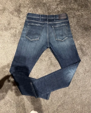 Replay jeans blå jondrill 33/32 - Snygga blå jeans från Replay i modellen jondrill med klassisk femficksdesign och diskret Replay-logga på bakfickan. Jeansen har en mörk tvätt med lätt slitning och är tillverkade i mjukt bomullsmaterial för skön passform. 