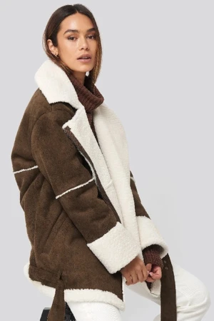 Brun teddyjacka med vita detaljer från NA-KD  - Säljer en brun teddyjacka från nakd  med breda vita fuskpälsdetaljer på krage, ärmslut och nederkant. Jackan har långärmad passform, dragkedja och coola sömmar som ger en schysst look. Perfekt för dig som vill ha en mysig och trendig jacka i vinter.