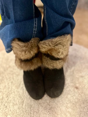 Kilklack stövletter. Passar både sommar och vinter. - Säljer ett par stilrena svarta stövletter med bekväm killklack och dekorativ fuskpäls runt ankeln. Trots den mysiga pälsdetaljen är skorna lätta och luftiga nog att använda även under svalare sommarkvällar. Samtidigt som de håller dig varm under vintern.