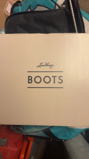 Nya Lundhags BC turskidpjäxor oanvända - Säljer ett par svarta boots från Lundhags med snygga röda detaljer och snörning. Skorna har robust platt sula, rund tå och är tillverkade i skinn och mocka. Perfekta för dig som gillar outdoor och vill ha stilrena kängor med coola metalldetaljer. Skorna är helt nya och oanvända. Skorna är köpta för ungefär 3400kr