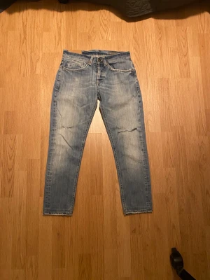 Dondup George - Snygga ljusblå skinny jeans från Dondup med slitningar på knäna och coola detaljer på bakfickorna. Klassisk femficksmodell med dragkedja och knapp framtill. Perfekt passform som sitter tight hela vägen ner. De är storlek 29 som passar dig som är runt 160-170