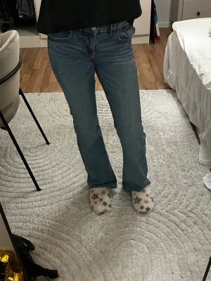 Blå bootcut jeans från Gina Tricot - Snygga blå jeans från Gina Tricot i storlek 164. Modellen har bootcut-ben, klassisk femficksdesign och dubbla silverfärgade knappar fram. Jeansen är tillverkade i jeansmaterial med kontrastsömmar och har en normal passform.