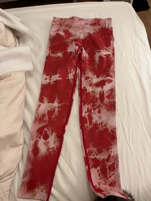 Röda tie-dye leggings från Rebel S - Snygga röda leggings från Rebel i storlek S med coolt tie-dye mönster i vitt. Högmidjade med ribbad linning och scrunch-detalj bak för extra shaping. Perfekta för träning eller chill. Stretchigt syntetmaterial som sitter skönt och följer kroppen. Pris kan diskuteras 
