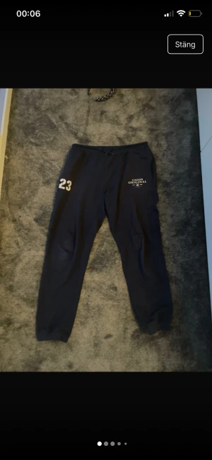 Svarta mjukisbyxor Vinson Original - Svarta mjukisbyxor från Vinson Original med tryckt nummer 23 på ena benet och logga på andra sidan. Byxorna har snörning i midjan och är gjorda i mjukt bomullsmaterial. Perfekta för chill eller sportiga dagar.