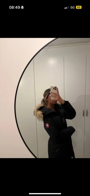 Svart Canada Goose dunjacka med päls - Säljer en svart lång Canada Goose dunjacka med huva och äkta päls. Jackan har klassisk patch på ärmen, stora fickor och stängs med både dragkedja och knappar. Perfekt för kalla vinterdagar och riktigt snygg passform.