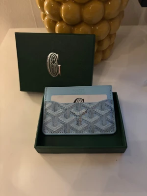 LjusBlå plånbok med mönster - Snygg ljusblå plånbok med det klassiska grafiska mönstret och logotypen tryckt på framsidan. 