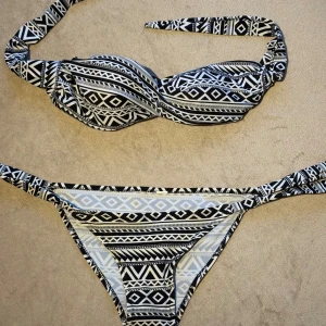 Bikini - Säljer en bikini i svart och vitt mönster. Tanken är att sälja överdelen då den är helt oanvänd.  Underdelen är använd och har en tråd som lossnat litegrann men självklart får man med den om man vill. storlek s