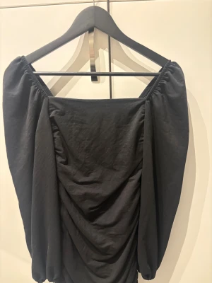 Svart klänning från Nelly - Säljer en svart kortare klänning från Nelly i storlek XS. Sitter tajt hela vägen men lite större ärmar, dragkedja baktill🖤använd fåtal gånger, så väldigt fint skick 